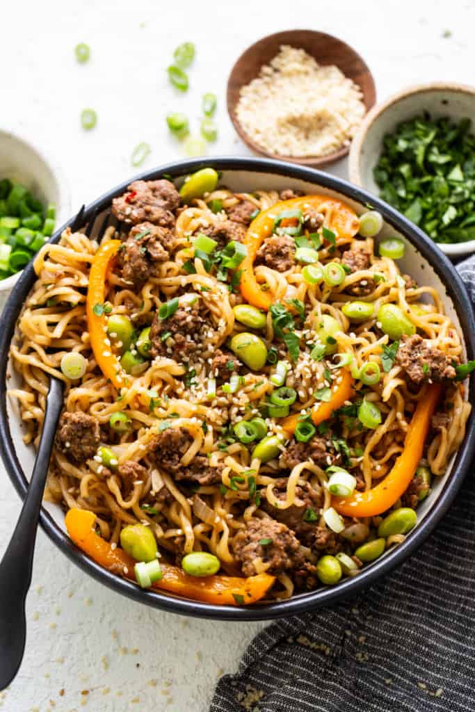 A bowl of noodles with beef and peppers.