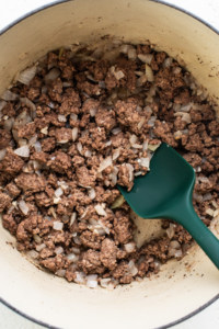 A pot filled with ground beef and onions.