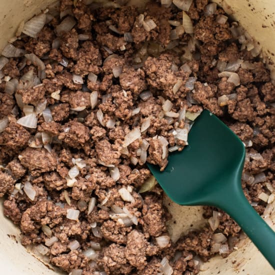 A pot filled with ground beef and onions.