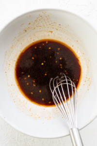 A bowl with brown liquid and a whisk.