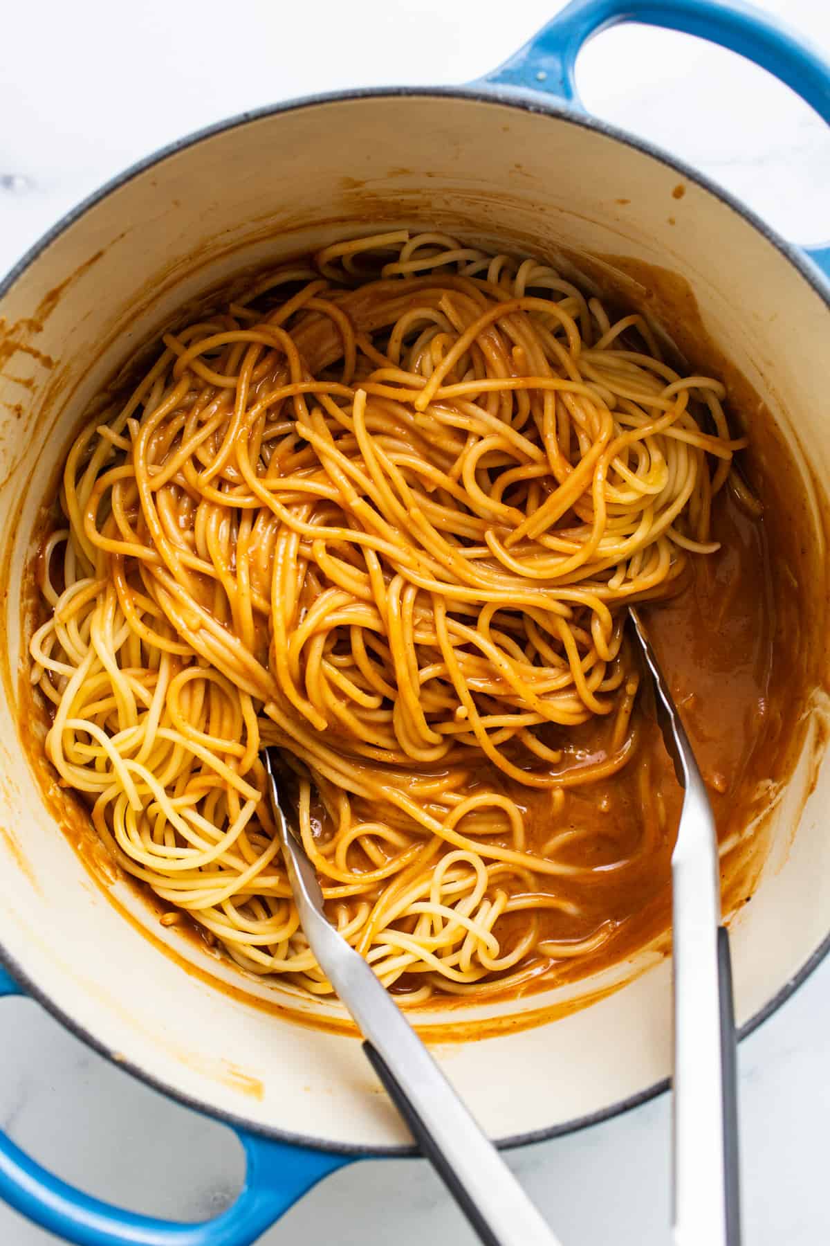 Spaghetti in a blue pot with two forks.