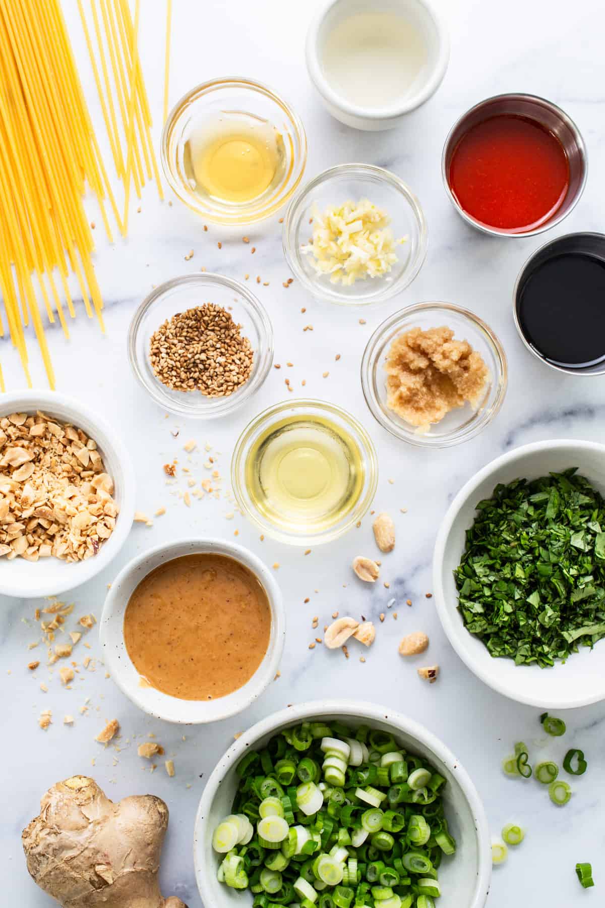 Ingredients for asian noodles on a white marble table.