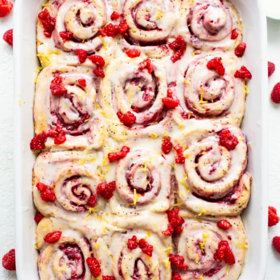 Raspberry cinnamon rolls in a white baking dish.