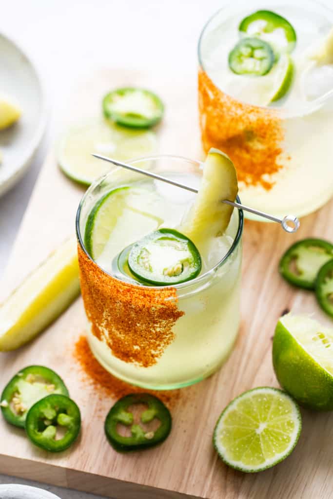A glass of drink with a pickle and lime slices.