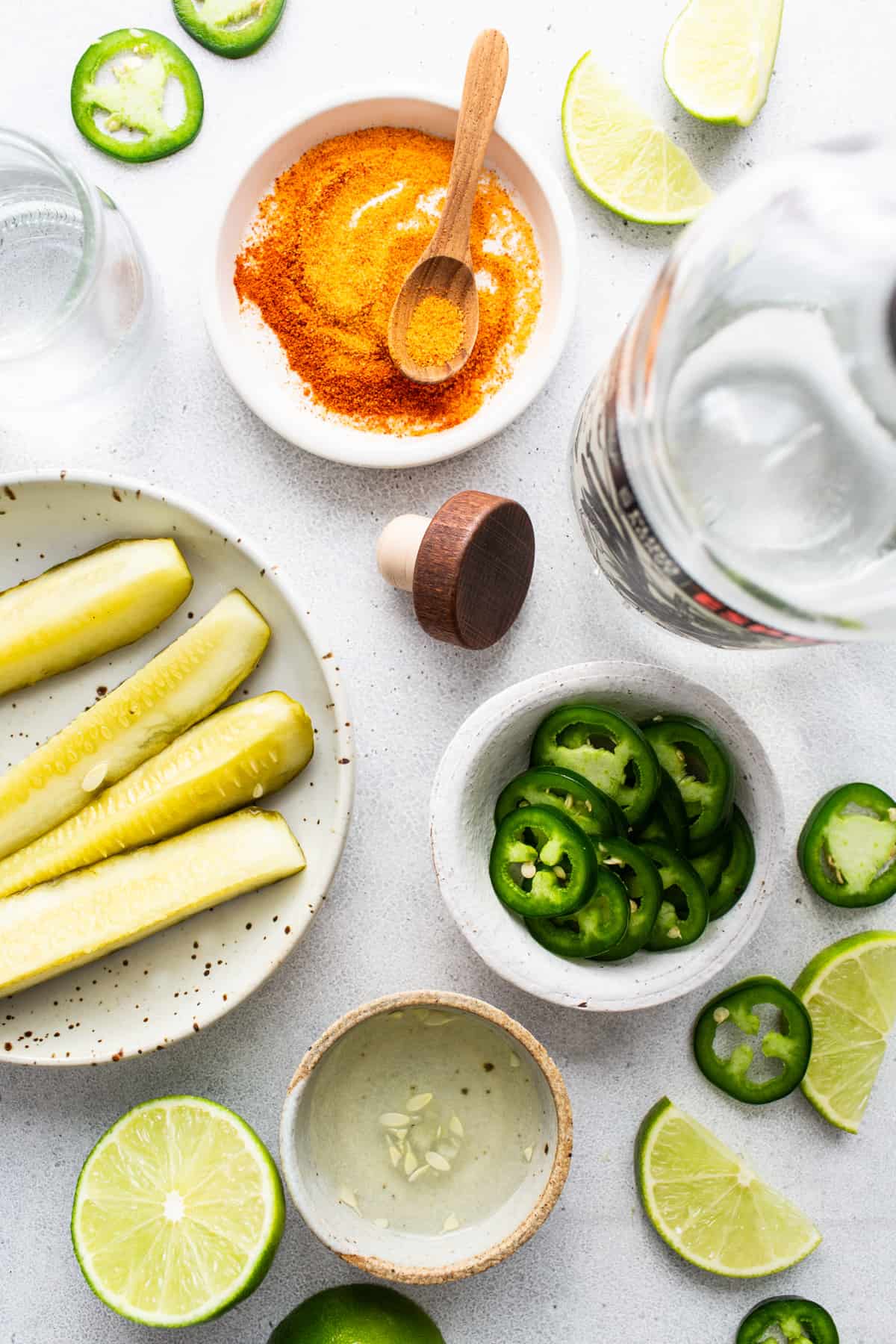 A plate with cucumbers, limes and a bottle of vodka.