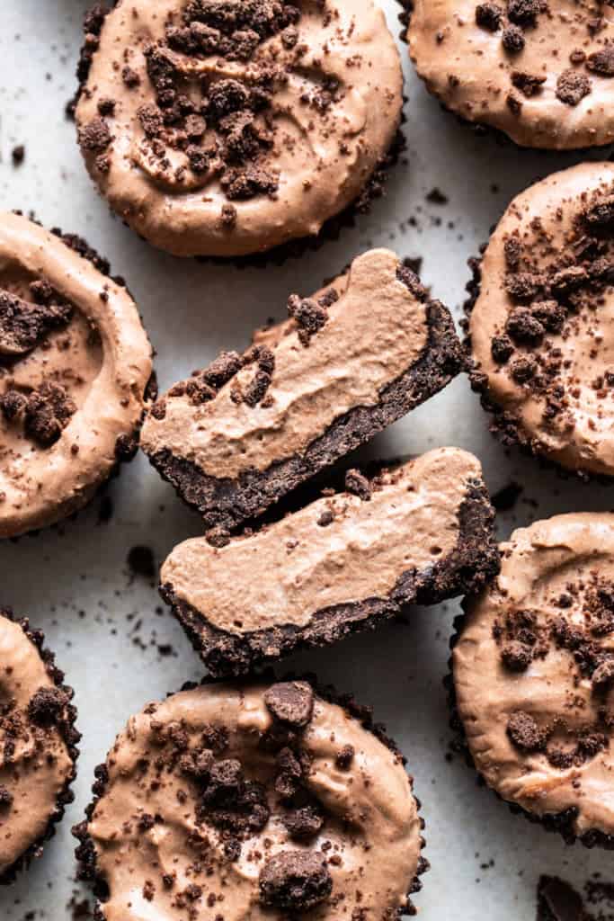 A group of chocolate cupcakes with a bite taken out of them.
