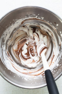 A bowl of chocolate whipped cream with a spatula.