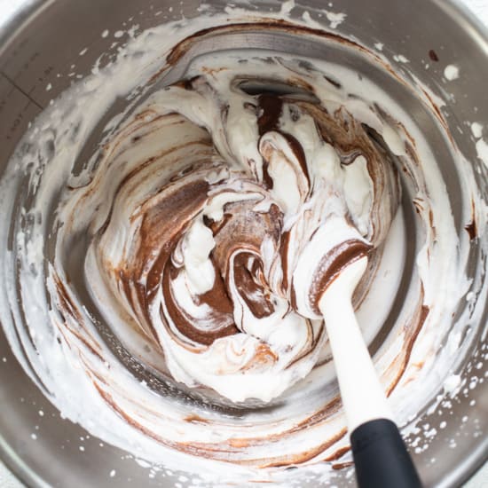A bowl of chocolate whipped cream with a spatula.