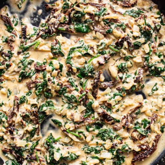 A skillet filled with spinach and mushrooms.