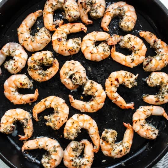 Grilled shrimp in a skillet with herbs.
