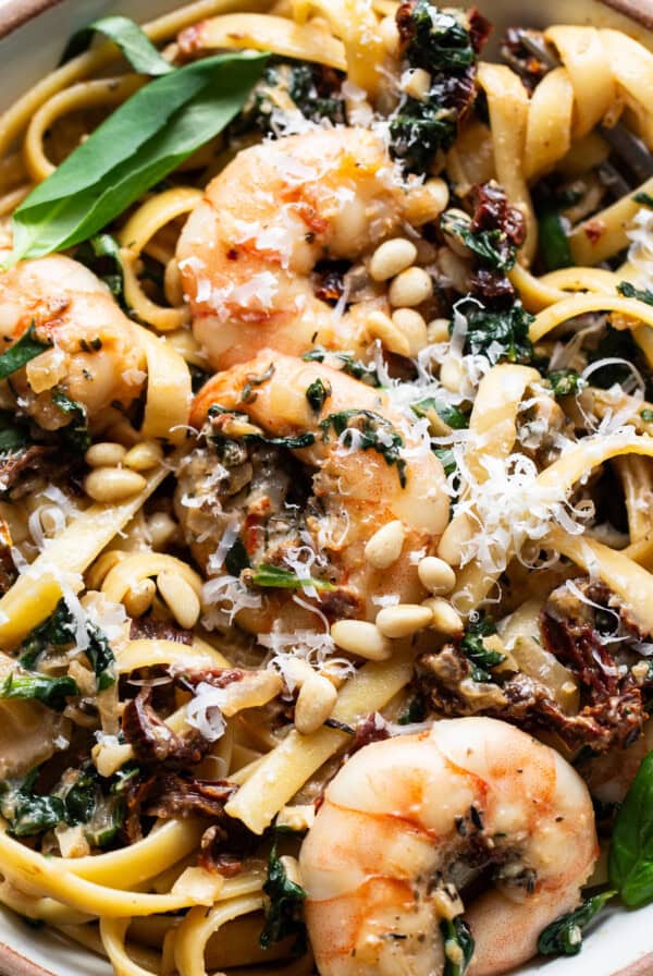 A bowl of pasta with shrimp and spinach.
