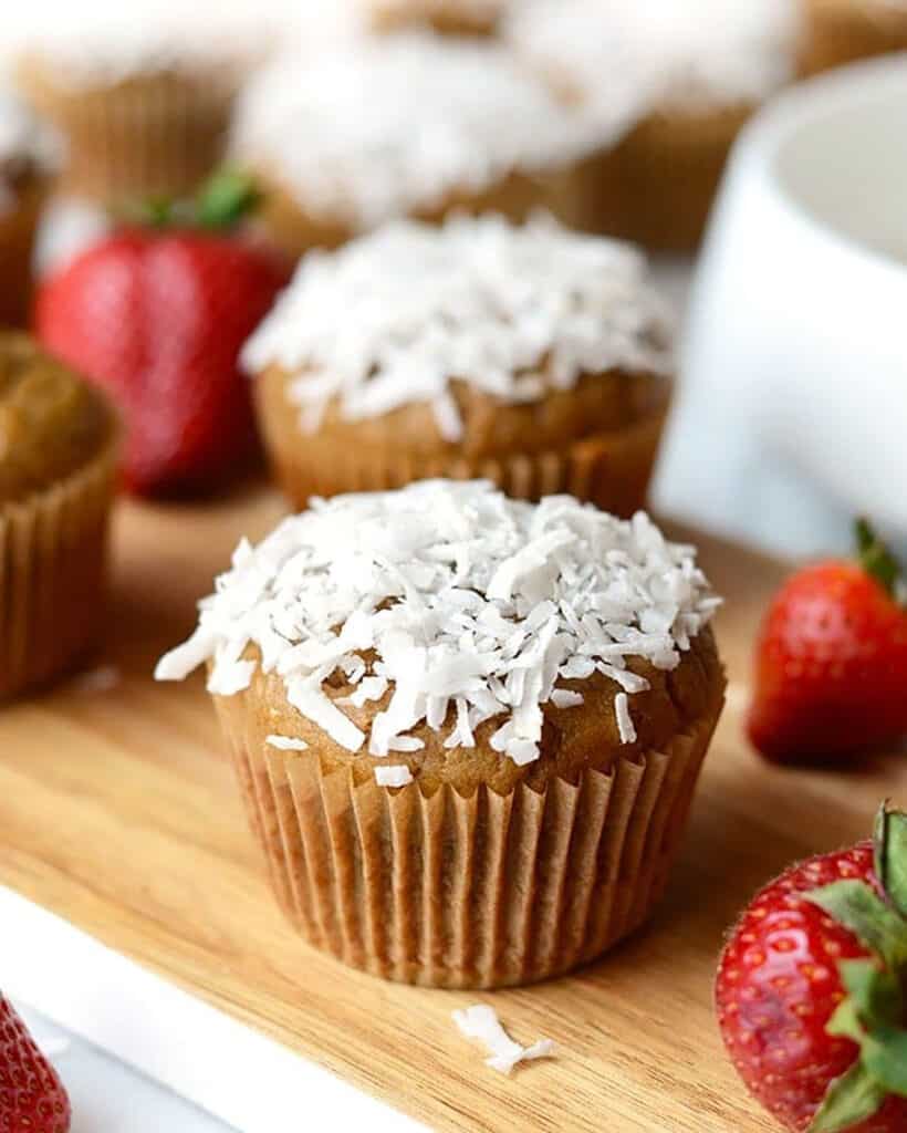Coconut cupcakes with strawberries on a wooden cutting board, perfect for a Blender Muffins party.