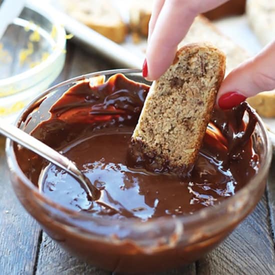 Dipping an almond flour biscotti into melted chocolate.