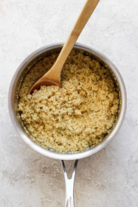 Cooked quinoa in a pot with a wooden spoon.