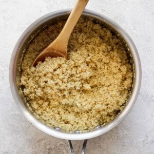 Cooked quinoa in a pot with a wooden spoon.