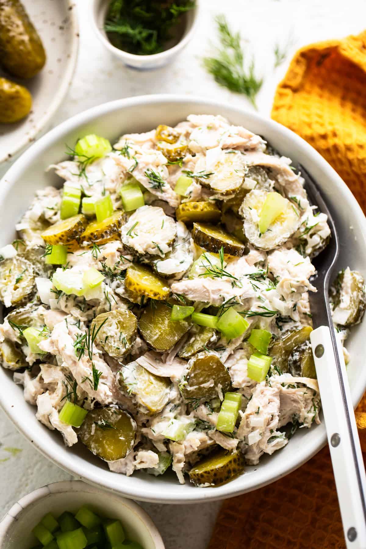Chicken and pickle salad garnished with dill in a serving dish.
