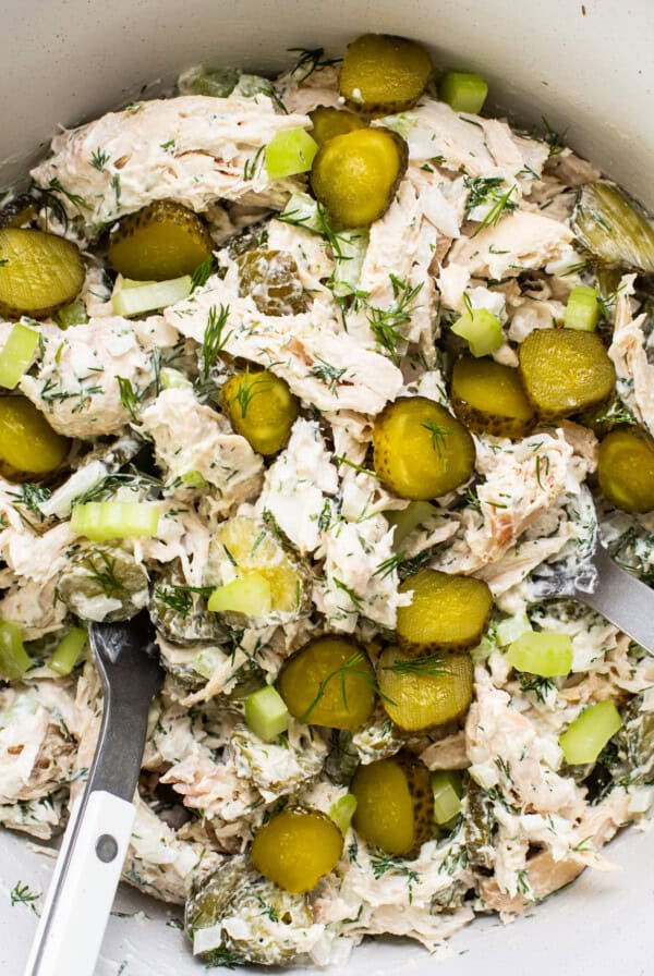 Bowl of tuna salad with pickles and herbs.