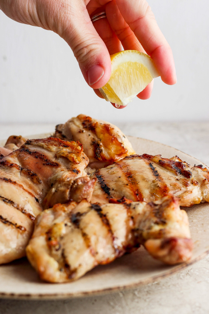 Squeezing lemon juice over grilled chicken breasts.