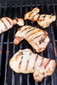 Grilled chicken breasts with grill marks on a barbecue grill.