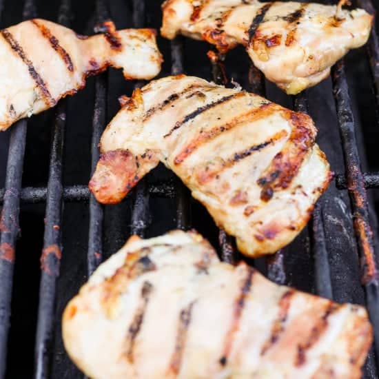Grilled chicken breasts with grill marks on a barbecue grill.