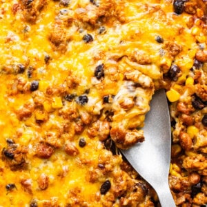 A skillet with baked cheesy casserole containing ground meat, black beans, and corn.