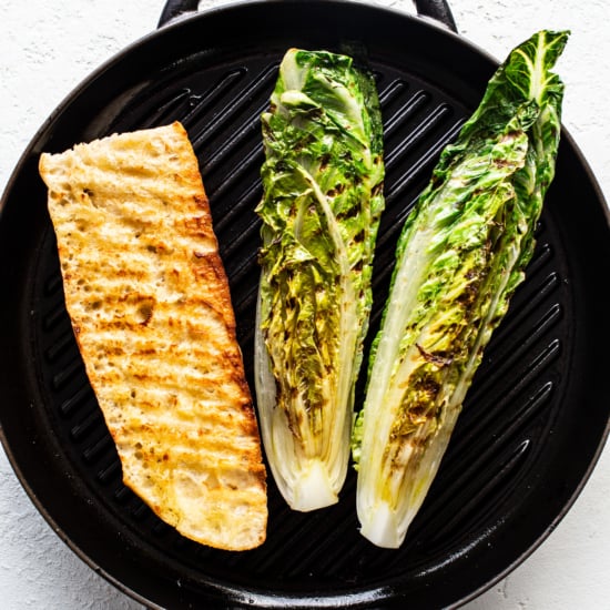 Grilled fish fillet and halves of romaine lettuce on a stove-top grill pan.