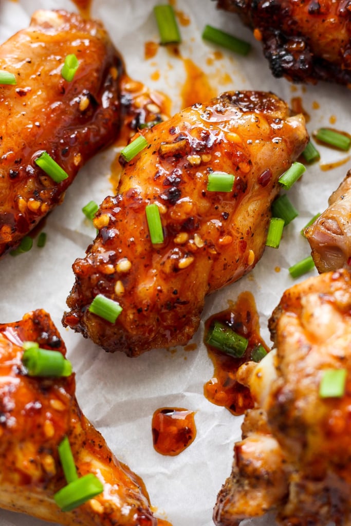 Glazed chicken wings sprinkled with sesame seeds and chopped green onions.