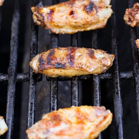 Grilled chicken wings on a barbecue grill with grill marks visible.