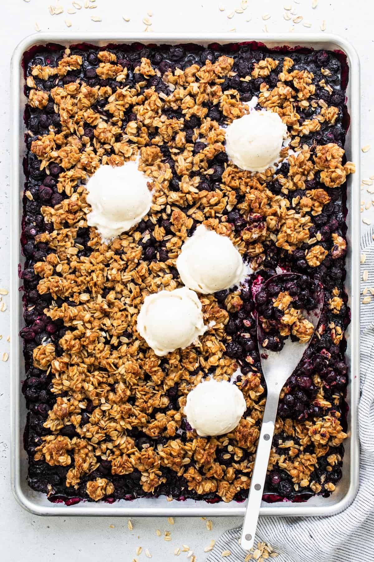 Freshly baked blueberry crumble with scoops of vanilla ice cream on top.