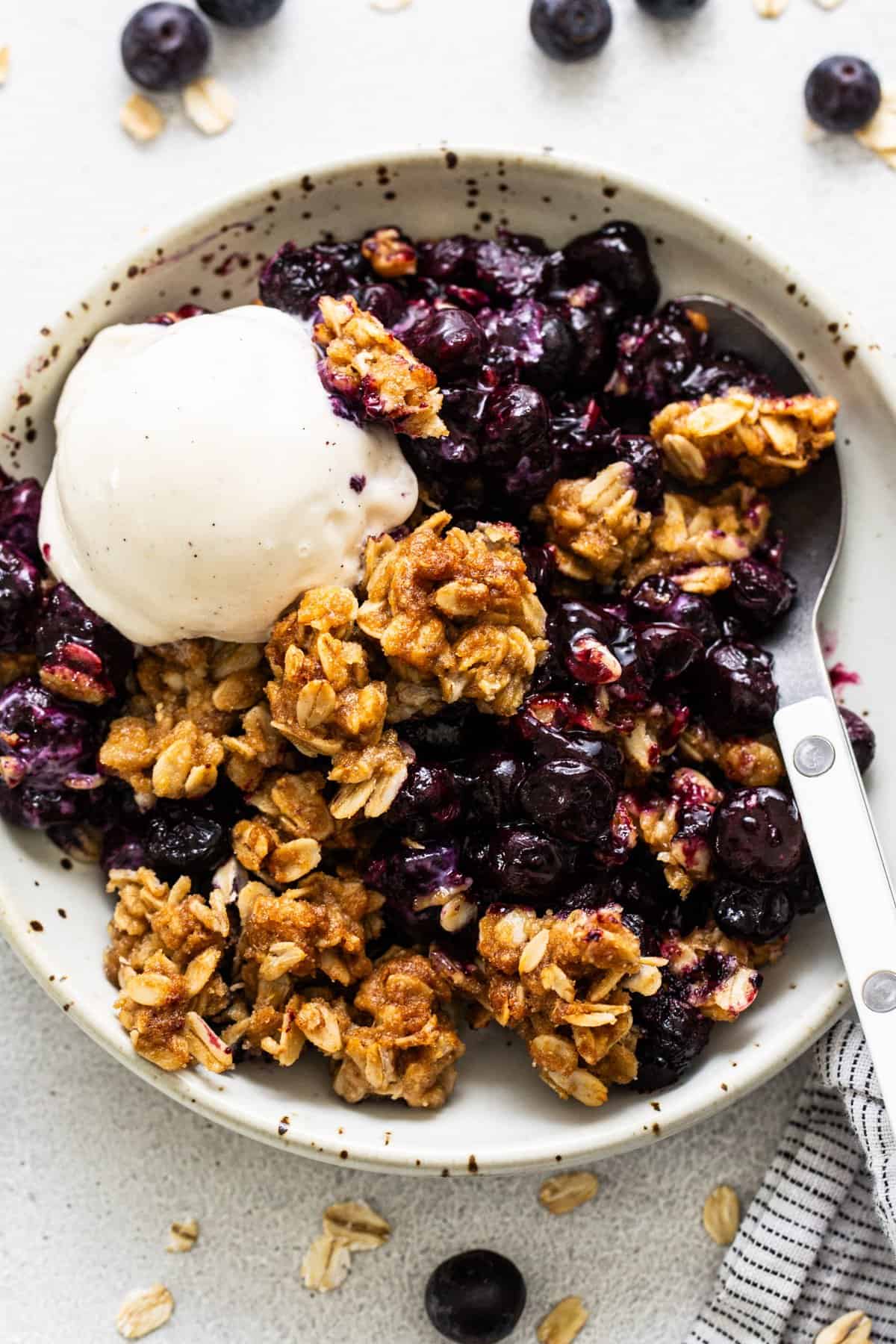 A bowl of blueberry c،ble topped with a scoop of vanilla ice cream.