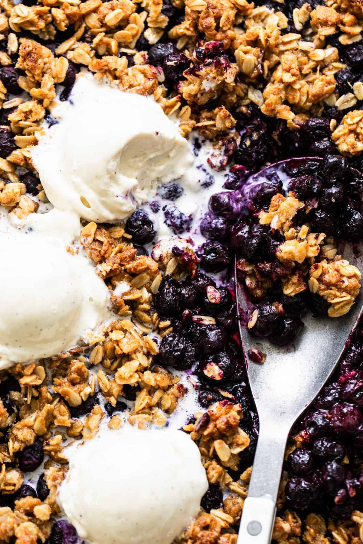 Baked blueberry crumble with scoops of vanilla ice cream.