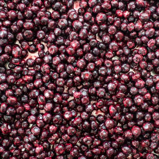 A close-up view of numerous dark red cherries piled together.