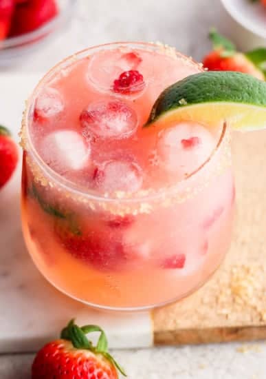 A refreshing strawberry cocktail garnished with a lime slice and served over ice.