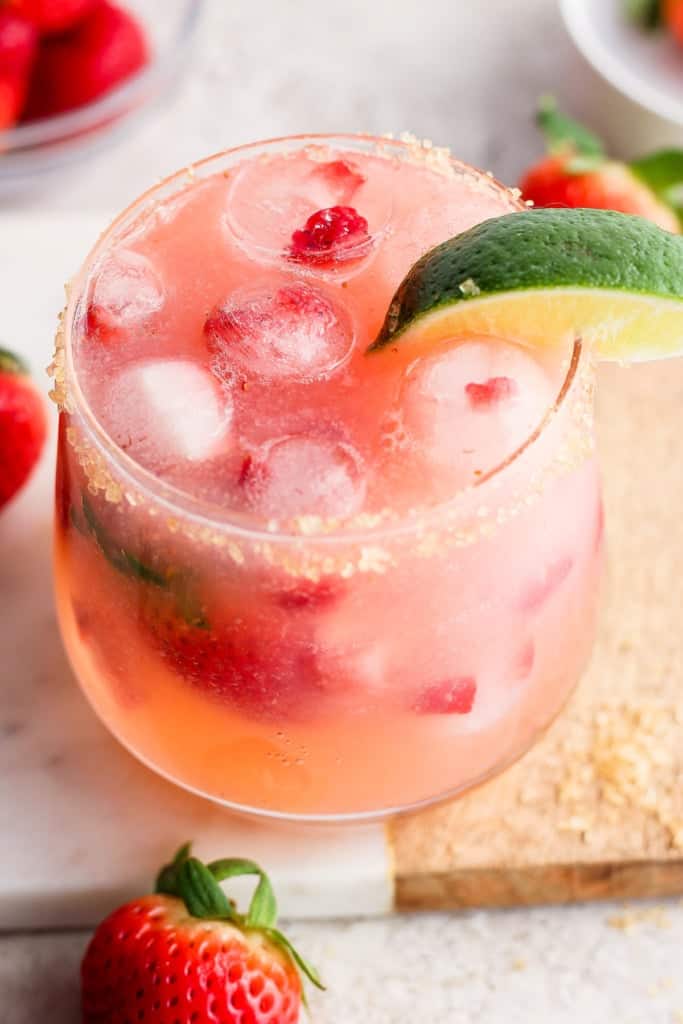 A refreshing strawberry cocktail garnished with a lime slice and served over ice.