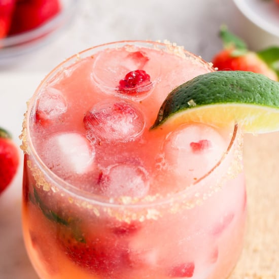 A refreshing strawberry cocktail with ice, lime, and a sugared rim.