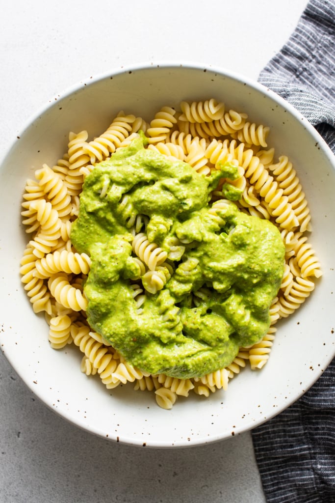 A bowl of rotini pasta topped with creamy green avocado sauce.