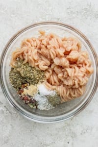 Cooked pasta with a variety of spices in a glass bowl.