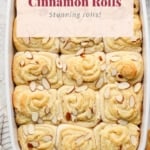 A tray of freshly baked almond croissant cinnamon rolls topped with almond slices.