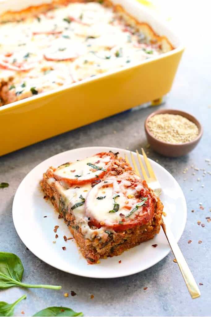 A slice of quinoa lasagna on a plate with a fork.