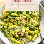 A bowl of sweet pea pesto pasta garnished with cheese and basil leaves, suggested as a healthy dinner idea.