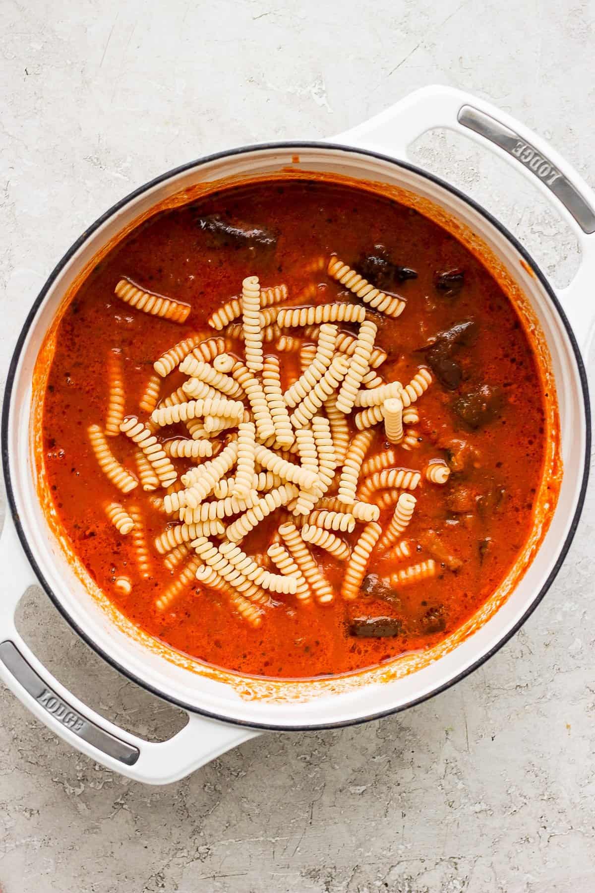 Pot of tomato soup with pasta on a kitchen counter.