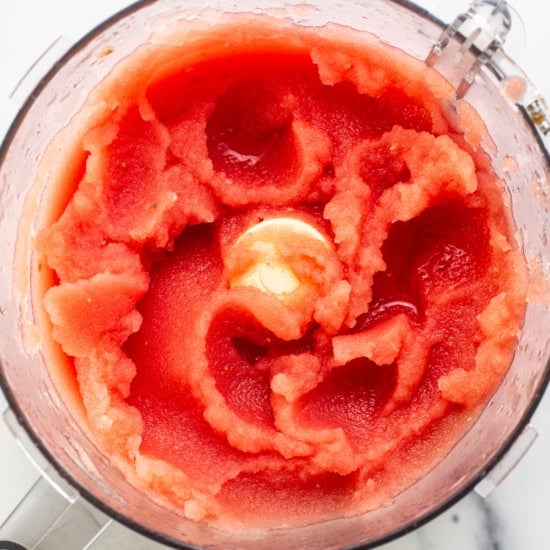 Top view of a blender filled with blended watermelon, showcasing a vivid red mixture with a swirling texture.