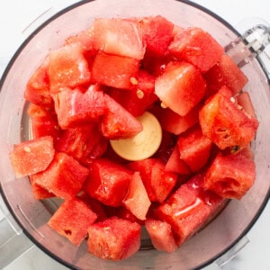 Chunks of fresh red watermelon in a food processor, ready for blending.