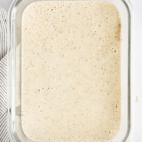 A glass container filled with oatmeal mixture is on a countertop.