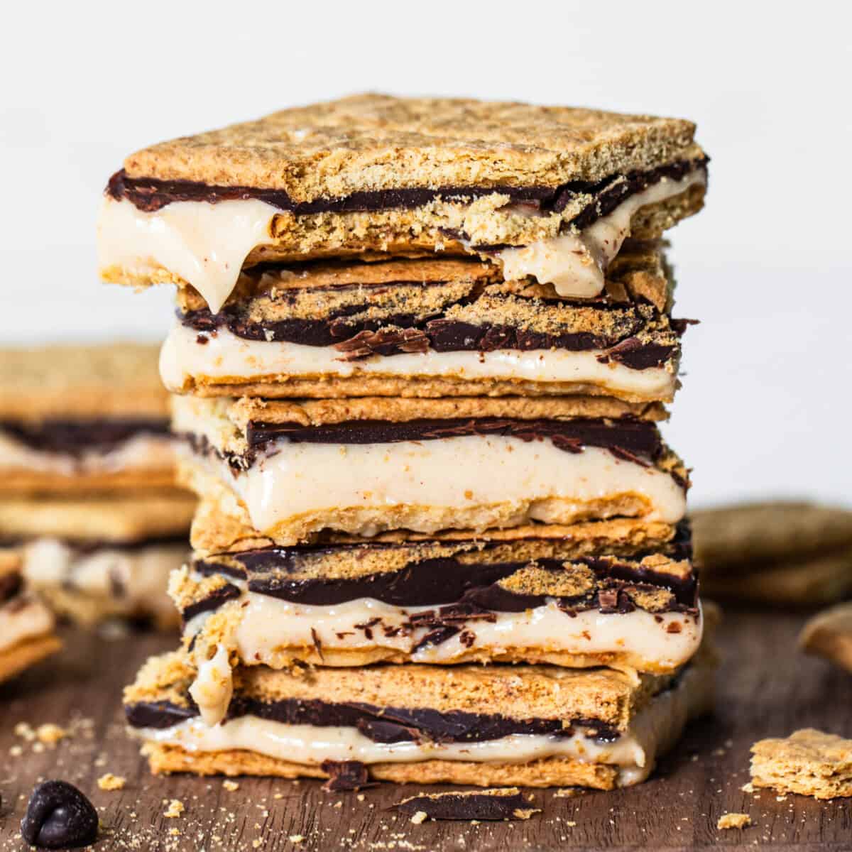 A stack of s'mores with melted marshmallows and chocolate between graham crackers, set against a wooden backdrop.