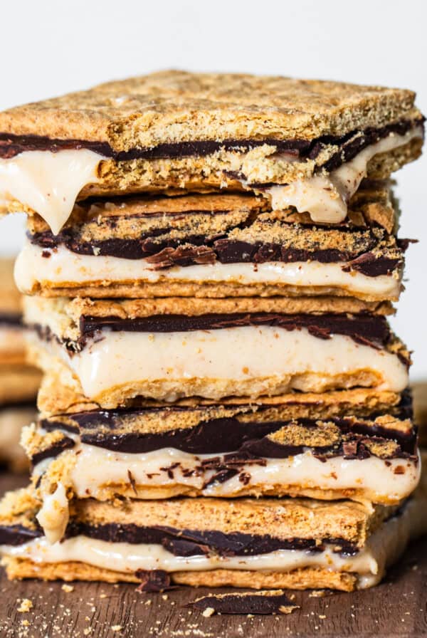 A stack of s'mores with melted marshmallows and chocolate between graham crackers, set against a wooden backdrop.