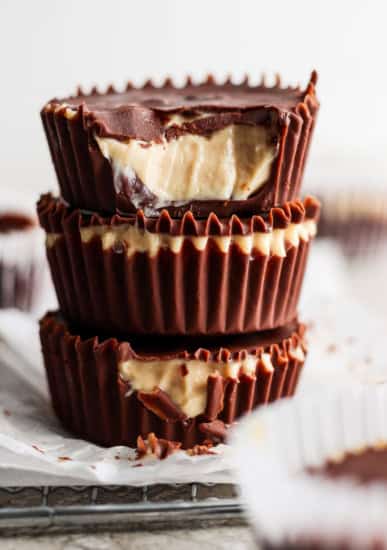 A stack of three homemade peanut butter cups with visible creamy peanut butter filling against a blurred background.