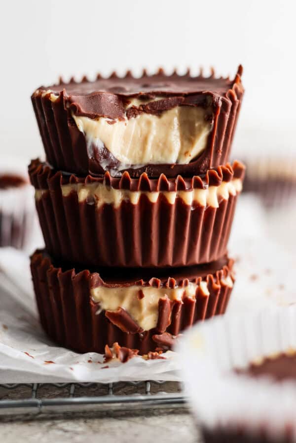 A stack of three homemade peanut butter cups with visible creamy peanut butter filling against a blurred background.