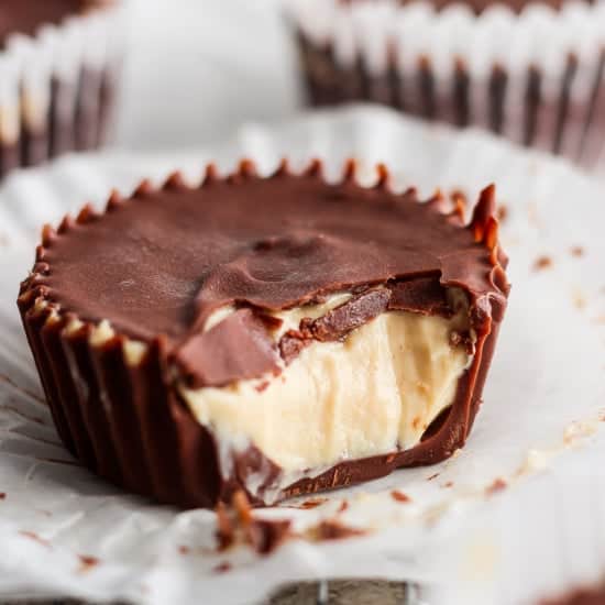 A close-up of a peanut butter cup with a bite taken out, revealing creamy peanut butter filling and a thick chocolate shell.