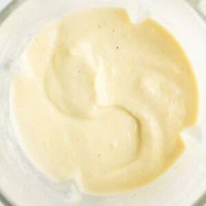 A close-up of a bowl containing smooth, creamy, beige-colored sauce or dressing.